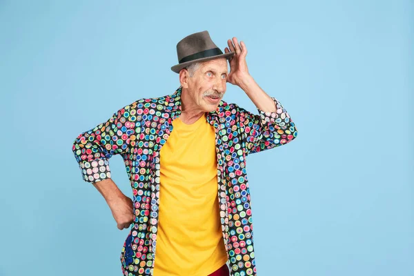 Senior hipster man in stylish hat isolated on blue background. Tech and joyful elderly lifestyle concept — Stock Photo, Image