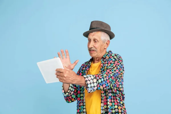 Hombre hipster senior con sombrero elegante aislado sobre fondo azul. Tecnología y alegre concepto de estilo de vida de ancianos — Foto de Stock