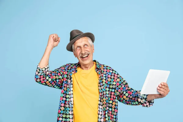 Hombre hipster senior con sombrero elegante aislado sobre fondo azul. Tecnología y alegre concepto de estilo de vida de ancianos — Foto de Stock