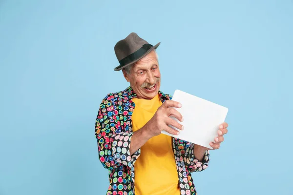 Hombre hipster senior con sombrero elegante aislado sobre fondo azul. Tecnología y alegre concepto de estilo de vida de ancianos — Foto de Stock