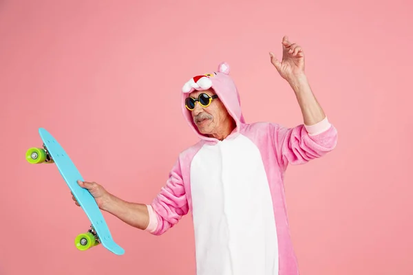 Starší hipster muž ve stylové růžové oblečení izolované na růžovém pozadí. Technický a radostný životní styl seniorů — Stock fotografie