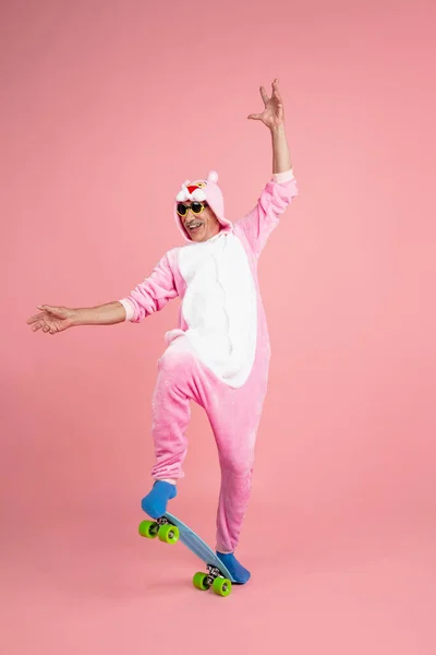 Senior hipster man in stijlvolle roze kleding geïsoleerd op roze achtergrond. Technisch en vrolijk ouderenlevensstijl concept — Stockfoto