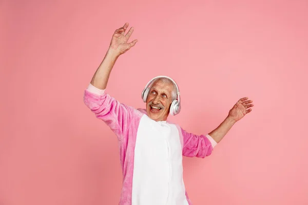 Senior hipster man in stijlvolle roze kleding geïsoleerd op roze achtergrond. Technisch en vrolijk ouderenlevensstijl concept — Stockfoto