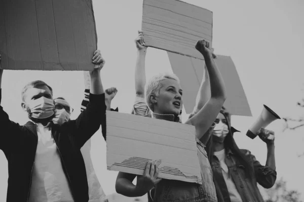 Group of activists giving slogans in a rally. Men and women marching together in a protest in the city.