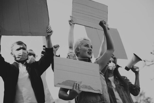 Группа активистов дает лозунги на митинге. Мужчины и женщины маршируют вместе в знак протеста в городе.