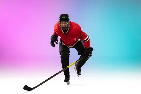 Male hockey player with the stick on ice court and neon colored gradient background. Sportsman wearing equipment, helmet practicing. — Stock Photo, Image