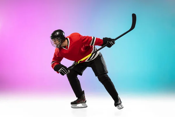 Чоловічий хокеїст з палицею на крижаному дворі і неоновим кольоровим градієнтним фоном. Спортсмен в обладнанні, шолом практикує . — стокове фото