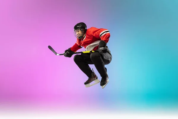 Férfi hoki játékos a bottal a jégpályán és neon színű gradiens háttér. Sportoló felszerelést visel, sisak gyakorló. — Stock Fotó