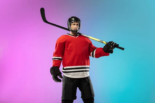 Jugador de hockey masculino con el palo en la pista de hielo y fondo degradado de color neón. Deportista con equipo, casco practicando. — Foto de Stock