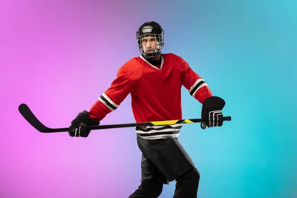 Männlicher Hockeyspieler mit dem Stock auf dem Eis und neonfarbenem Hintergrund. Sportler trägt Ausrüstung, Helm. — Stockfoto