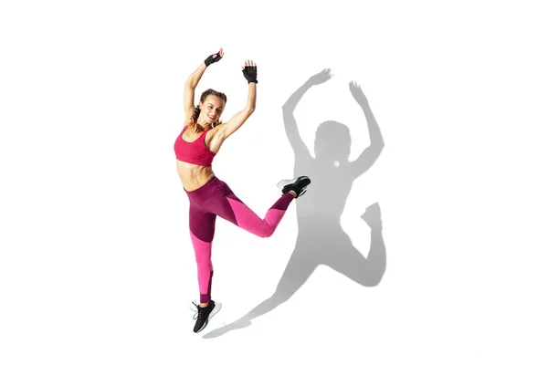 Beautiful young female athlete practicing on white studio background with shadows — Stock Photo, Image