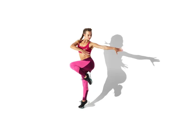 Beautiful young female athlete practicing on white studio background with shadows — Stock Photo, Image