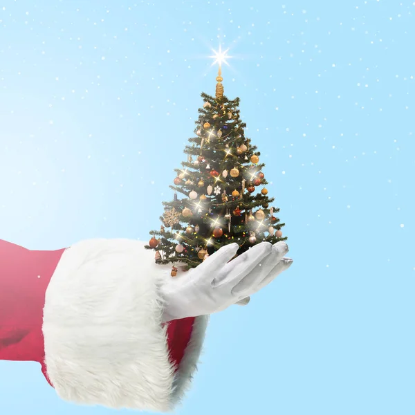 Санта-Клаусс тримає прикрашене дерево Крістамс ізольоване на синьому тлі. New Year 2021, copyspace. — стокове фото