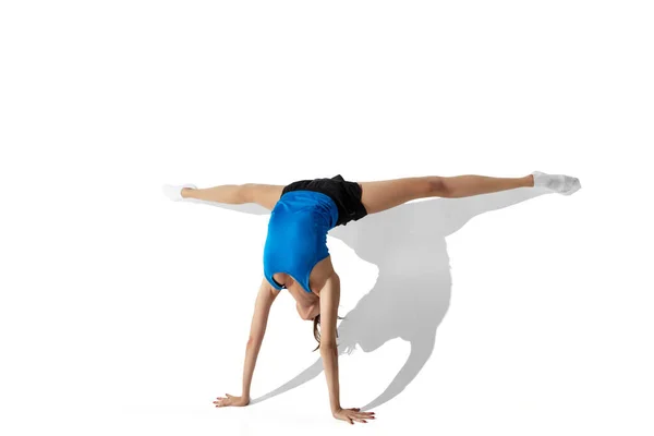 Beautiful young female athlete stretching on white studio background with shadows — Stock Photo, Image