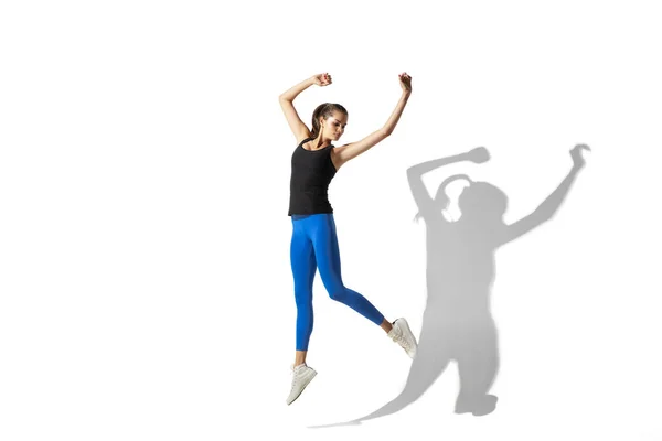 Beautiful young female athlete stretching on white studio background with shadows — Stock Photo, Image