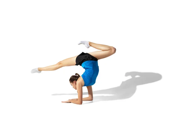 Beautiful young female athlete stretching on white studio background with shadows — Stock Photo, Image