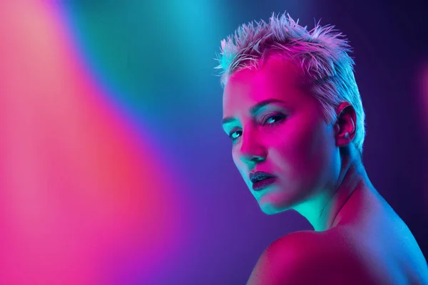 Portrait of female fashion model in neon light on dark studio background. — Stock Photo, Image