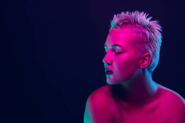 Karanlık stüdyo arka planında neon ışıklı kadın model portresi.