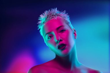 Karanlık stüdyo arka planında neon ışıklı kadın model portresi.