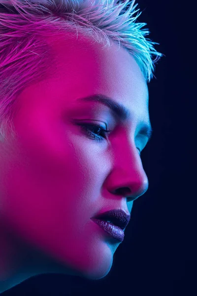 Portret van vrouwelijke mode model in neon licht op donkere studio achtergrond. — Stockfoto