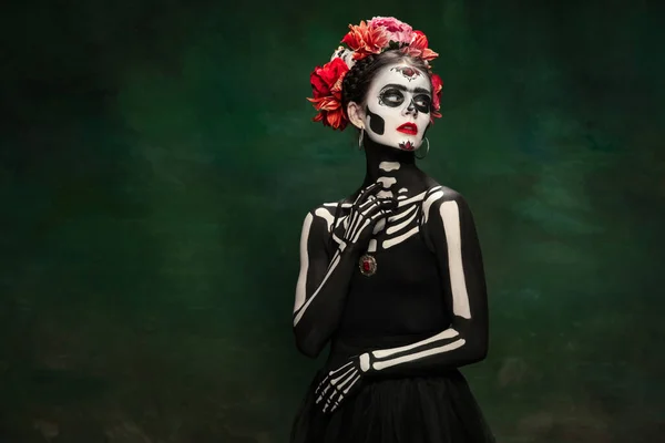 Jong meisje naar het beeld van Santa Muerte, Sint dood of Suikerschedel met heldere make-up. Portret geïsoleerd op studio achtergrond. — Stockfoto