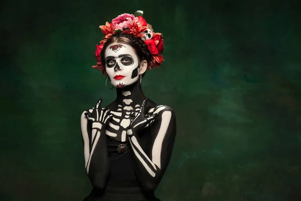 Jong meisje naar het beeld van Santa Muerte, Sint dood of Suikerschedel met heldere make-up. Portret geïsoleerd op studio achtergrond. — Stockfoto