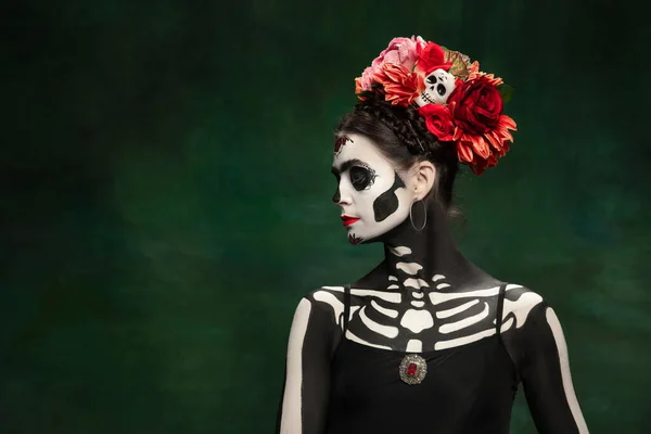 Jong meisje naar het beeld van Santa Muerte, Sint dood of Suikerschedel met heldere make-up. Portret geïsoleerd op studio achtergrond. — Stockfoto