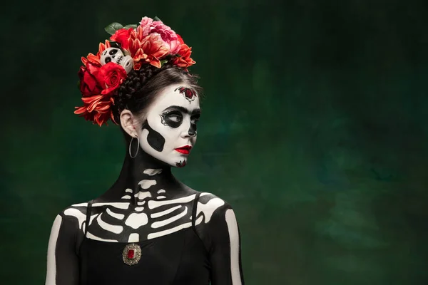 Jong meisje naar het beeld van Santa Muerte, Sint dood of Suikerschedel met heldere make-up. Portret geïsoleerd op studio achtergrond. — Stockfoto