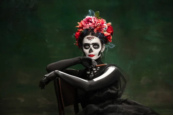 Jong meisje naar het beeld van Santa Muerte, Sint dood of Suikerschedel met heldere make-up. Portret geïsoleerd op studio achtergrond. — Stockfoto