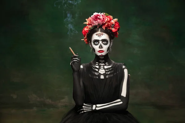 Jong meisje naar het beeld van Santa Muerte, Sint dood of Suikerschedel met heldere make-up. Portret geïsoleerd op studio achtergrond. — Stockfoto