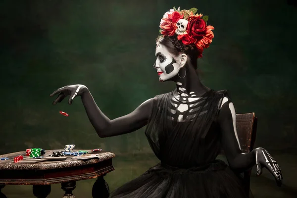 Jong meisje naar het beeld van Santa Muerte, Sint dood of Suikerschedel met heldere make-up. Portret geïsoleerd op studio achtergrond. — Stockfoto