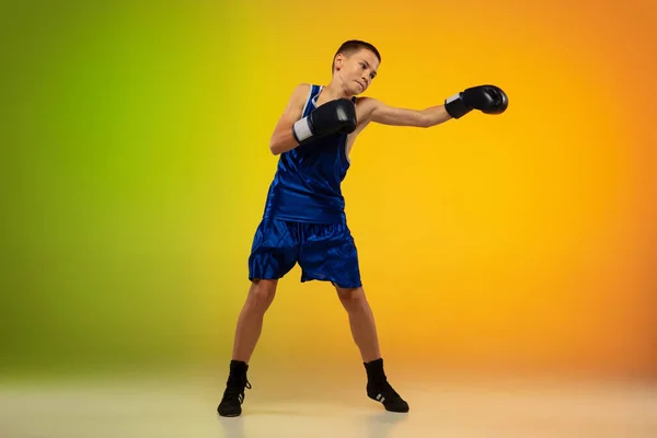 Adolescente boxer contra gradiente neon estúdio fundo em movimento de chutar, boxe — Fotografia de Stock