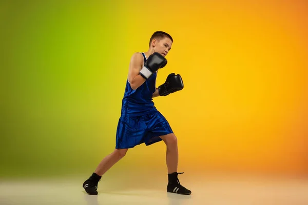 Teenage boxer proti gradient neon studio pozadí v pohybu kopání, box — Stock fotografie
