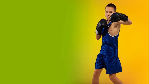 Boxeador adolescente contra gradiente neón fondo del estudio en movimiento de patadas, boxeo — Foto de Stock