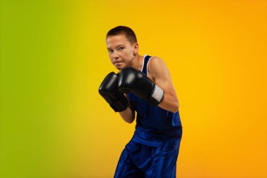 Genç boksör, neon stüdyonun arka planına karşı tekmeleme ve boks yapıyor.