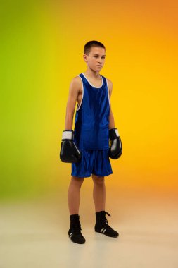 Genç boksör, neon stüdyonun arka planına karşı tekmeleme ve boks yapıyor.