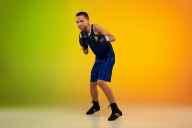 Genç boksör, neon stüdyonun arka planına karşı tekmeleme ve boks yapıyor.