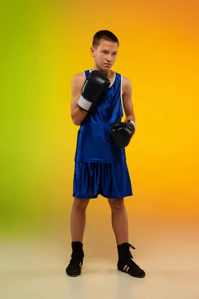 Boxeador adolescente contra gradiente neón fondo del estudio en movimiento de patadas, boxeo —  Fotos de Stock