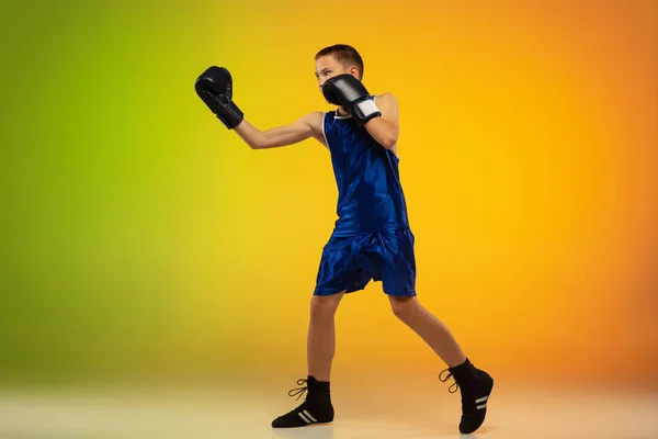 Teenage boxer proti gradient neon studio pozadí v pohybu kopání, box — Stock fotografie