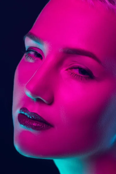 Portret van vrouwelijke mode model in neon licht op donkere studio achtergrond. — Stockfoto