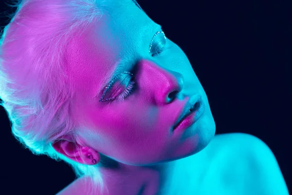 Portrait of beautiful albino girl isolated on dark studio background in neon light — Stock Photo, Image