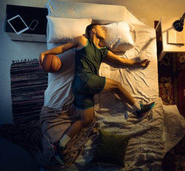 Genç profesyonel basketbolcunun yatak odasında spor giysisiyle uyuduğu en iyi manzara.