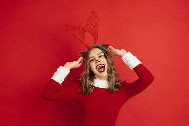 Kırmızı arka planda izole edilmiş Noel geyiği gibi güzel bir kadın. 2021 Yeni Yıl kavramı, kış havası, tatiller.