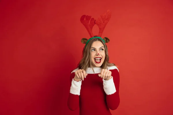 Krásná žena jako vánoční jelen izolované na červeném pozadí. Koncept 2021 Nový rok, zimní nálada, svátky. — Stock fotografie