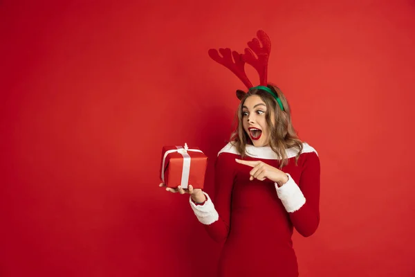 Krásná žena jako vánoční jelen izolované na červeném pozadí. Koncept 2021 Nový rok, zimní nálada, svátky. — Stock fotografie