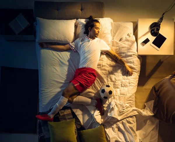 Vista superior de fútbol joven profesional, jugador de fútbol durmiendo en su dormitorio en ropa deportiva con pelota —  Fotos de Stock