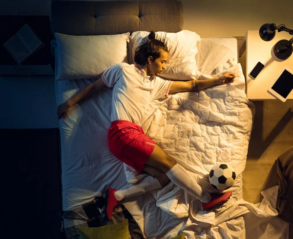 Vista superior de fútbol joven profesional, jugador de fútbol durmiendo en su dormitorio en ropa deportiva con pelota — Foto de Stock
