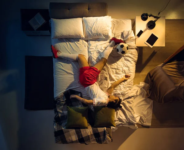 Vista superior de fútbol joven profesional, jugador de fútbol durmiendo en su dormitorio en ropa deportiva con pelota —  Fotos de Stock