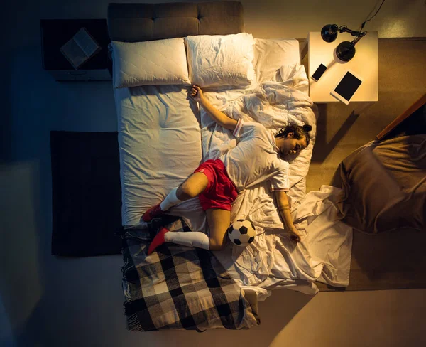 Vista superior de fútbol joven profesional, jugador de fútbol durmiendo en su dormitorio en ropa deportiva con pelota —  Fotos de Stock