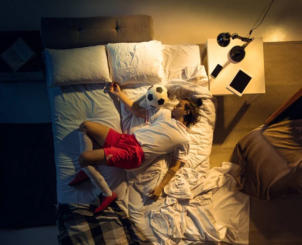 Vista superior de fútbol joven profesional, jugador de fútbol durmiendo en su dormitorio en ropa deportiva con pelota —  Fotos de Stock